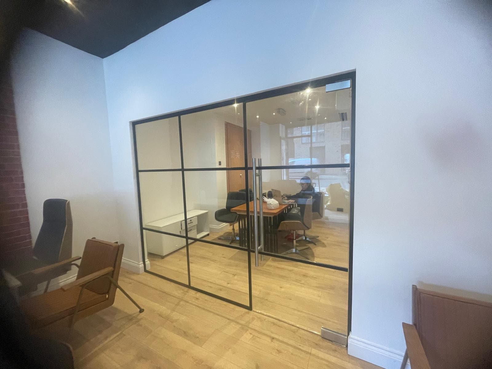 Black-framed internal glazed screen with a glazed door, set in a newly fitted office
