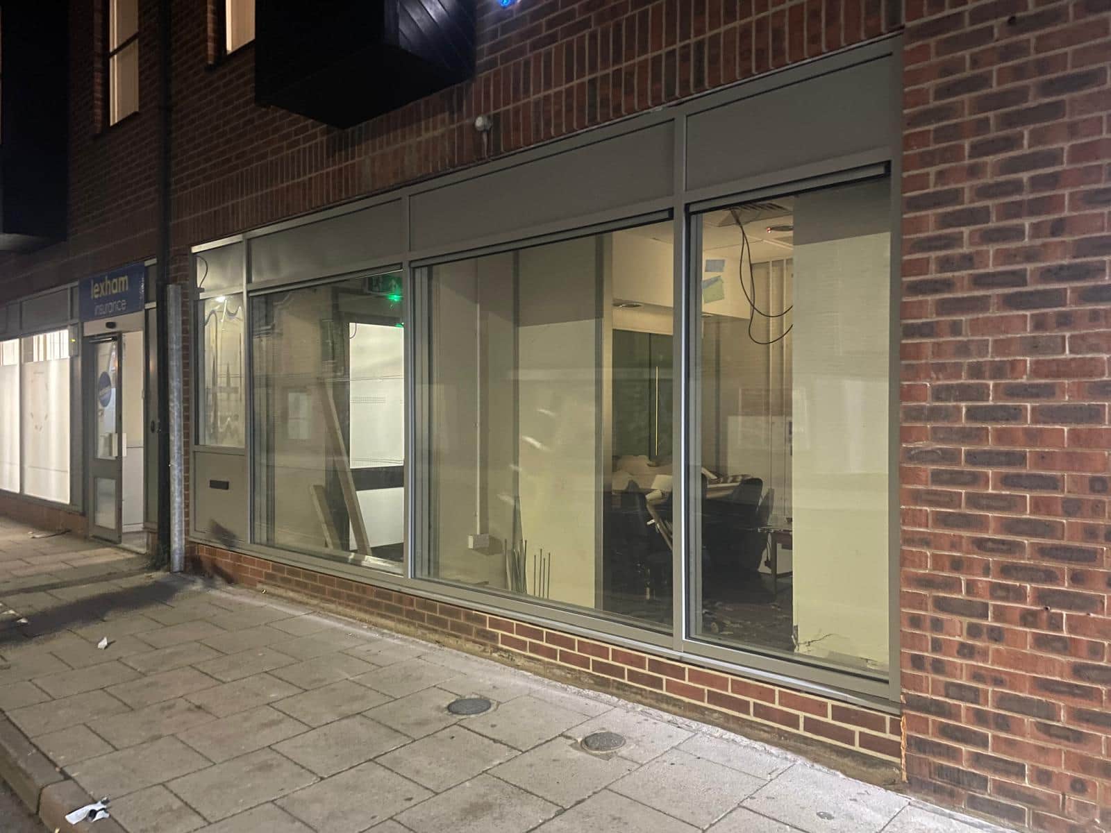 Ground-floor commercial unit with new full-height aluminium glazing set between brick piers.