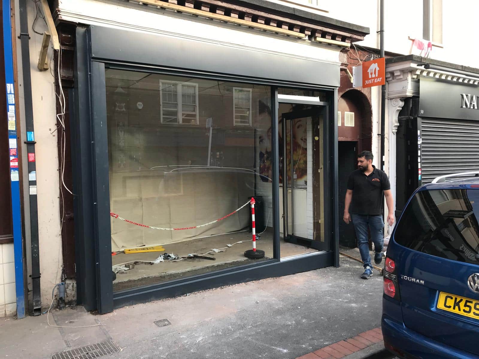 A new aluminium shopfront frame and entrance door going in, with the site still taped off.