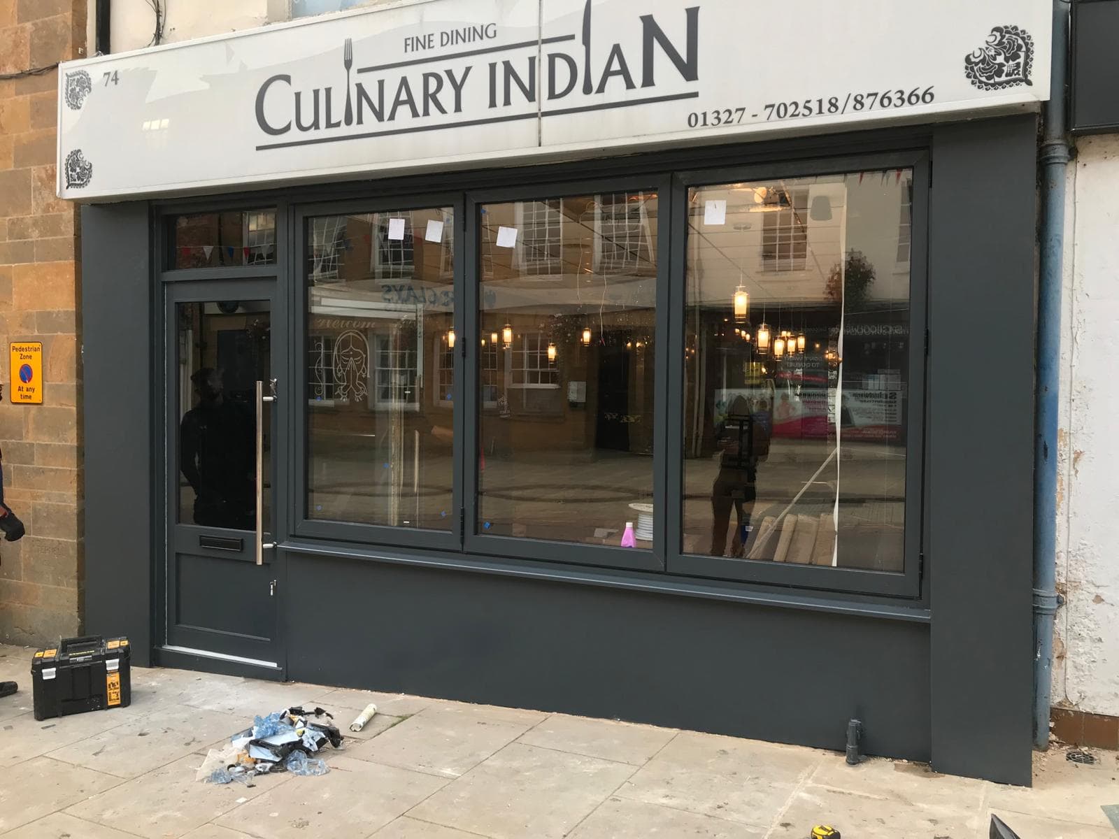 Dark grey aluminium shopfront with a glazed entrance door, fixed glazing and a painted fascia above
