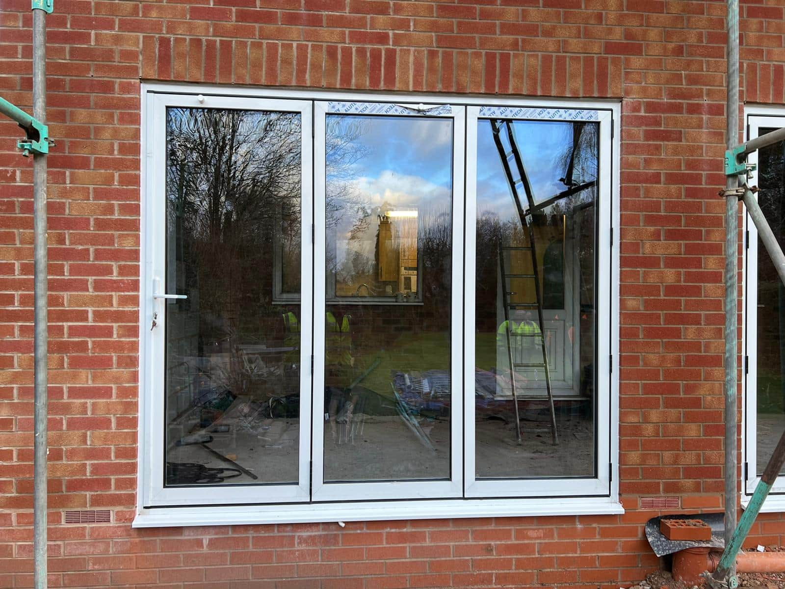 White-framed glazed doors and side panels installed in a brick opening.